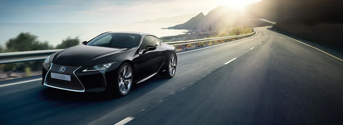 Čierny Lexus LC 500h na pobrežnej ceste v protisvetle