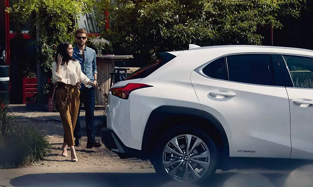 Elegantný pár pri bielom hybridnom vozidle Lexus.